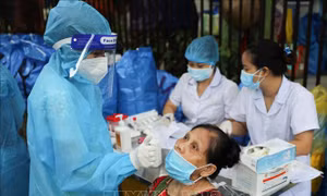 Lấy mẫu test nhanh cho người dân đến nhận quà hỗ trợ tại "Chợ nhân đạo". Ảnh: Thanh Tùng -TTXVN 