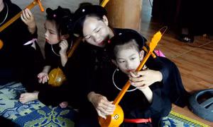 Chị Đàm Thanh Hiền hướng dẫn các cháu nhỏ cách chơi đàn Tính. Ảnh: Quang Cường - TTXVN 