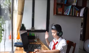 Học sinh Trường THCS Tương Bình Hiệp, thành phố Thủ Dầu Một, chào cô giáo và các bạn cùng lớp trên lớp học trực tuyến. Ảnh: Chí Tưởng -TTXVN 