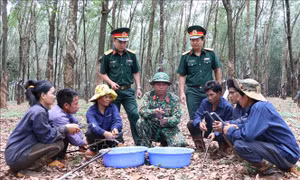 Anh Kpui Sinh, dân tộc Jrai, tổ trưởng Tổ 3, Đội 10, Công ty 74, Binh đoàn 15 (giữa, hàng trước) đảng viên người dân tộc thiểu số hướng dẫn cho công nhân cách mài dao cạo mủ cao su. Ảnh: Hồng Điệp - TTXVN
