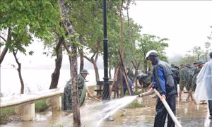 Các lực lượng dọn dẹp bùn đất tại khu vực 2 bên bờ sông Hương. Ảnh: Tường Vi - TTXVN