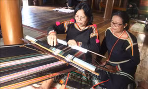 Bà H’Yam (phải), Giám đốc Hợp tác xã Dệt thổ cẩm Tơng Bông quan sát, hướng dẫn xã viên dệt thổ cẩm. Ảnh: Hoài Thu – TTXVN