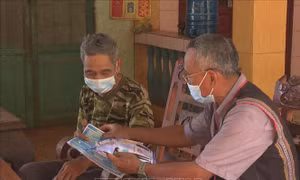 Ông Điểu Blô tuyên truyền phòng, chống COVID-19 tại nhà cho người dân trong ấp. Ảnh: K GỬIH-TTXVN 