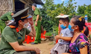 Nữ cán bộ Công an TP Cần Thơ trò chuyện với bé Nguyễn Huỳnh Gia Bảo (xã Tân Thới, huyện Phong Điền) có cha mất do COVID-19. Ảnh: Thanh Liêm - TTXVN 