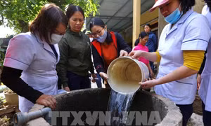 Nhân viên y tế tiến hành pha dung dịch hóa chất rồi đổ xuống giếng theo đúng quy trình và tỷ lệ cho phép để xử lý nguồn nước sinh hoạt an toàn cho người dân . Ảnh: Minh Quyết - TTXVN