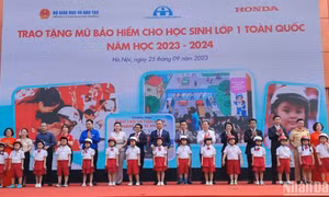 Đại diện Ban tổ chức trao tặng mũ bảo hiểm cho các em học sinh Trường tiểu học Phú Đô (Hà Nội). Ảnh: nhandan.vn