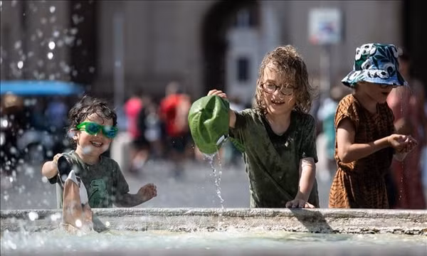 Trẻ em làm mát bên đài phun nước trong ngày nắng nóng ở Rome, Italy. Ảnh: THX/TTXVN