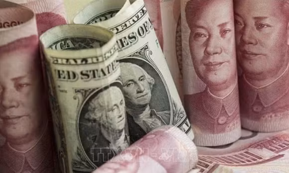 Đồng NDT và đồng USD tại một ngân hàng ở Bắc Kinh, Trung Quốc. Ảnh: AFP/TTXVN (Ảnh không cho phép bên thứ ba khai thác, chia sẻ lại)