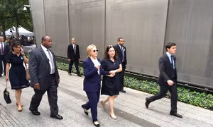 Người phụ nữ bí ẩn mặc đầm xanh theo sát bà Clinton là ai?