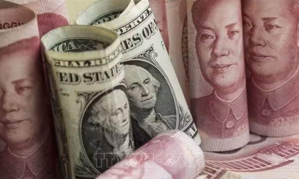 Đồng NDT và đồng USD tại một ngân hàng ở Bắc Kinh, Trung Quốc. Ảnh: AFP/TTXVN (Ảnh không cho phép bên thứ ba khai thác, chia sẻ lại)