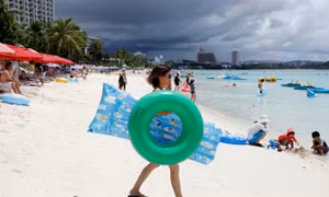 Mặc Triều Tiên dọa tấn công, du khách đảo Guam vẫn tắm biển, lướt sóng