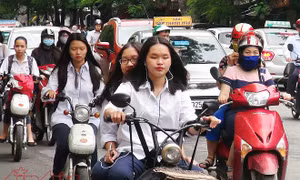 Học sinh hồn nhiên đi xe điện không đội mũ bảo hiểm