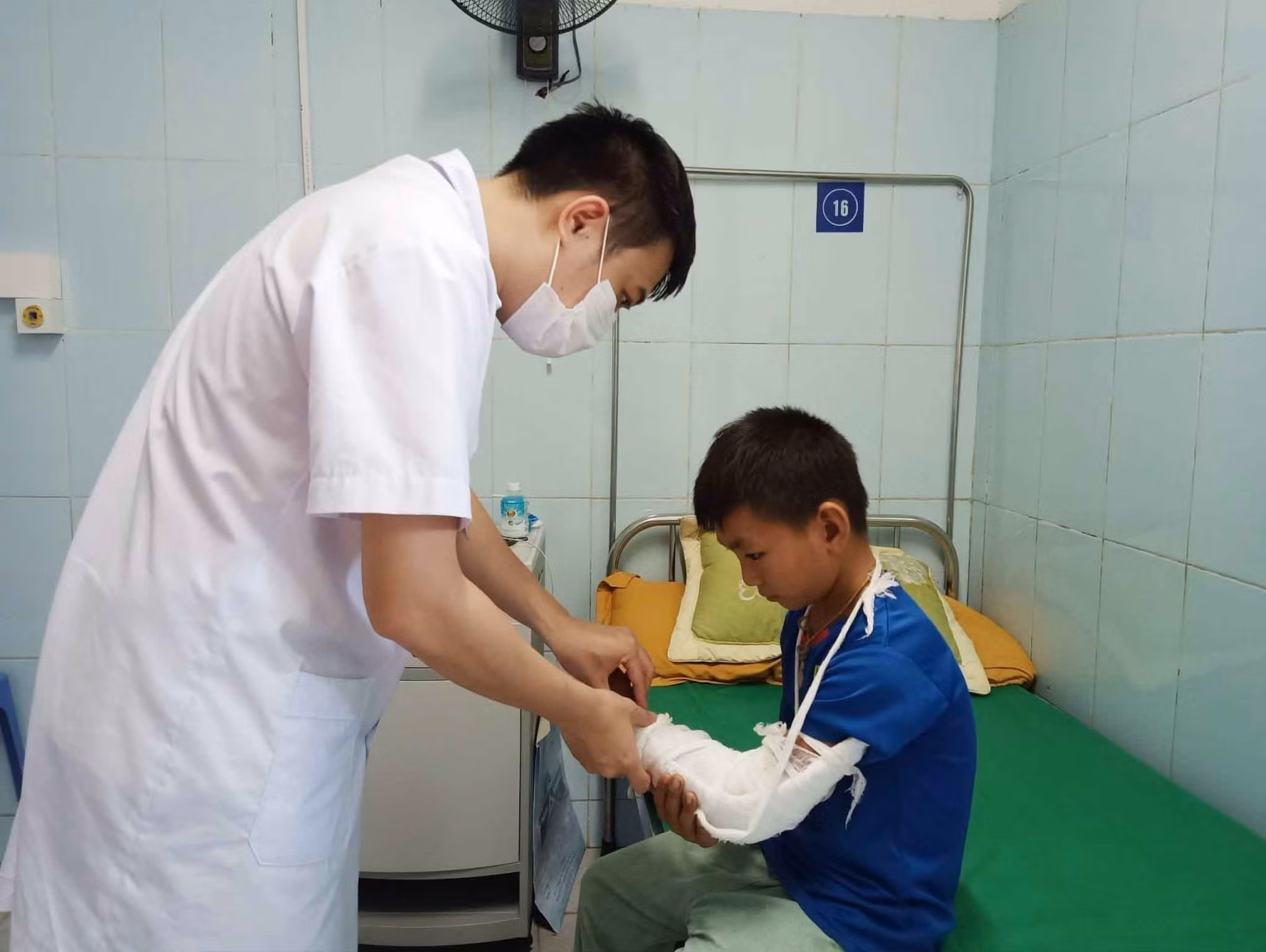 Bác sỹ Bệnh viện Đa khoa tỉnh Lai Châu kiểm tra vết thương cho cháu Hạng A Chù, xã Tả Lèng, huyện Tam Đường do đắp lá cây rừng gây phỏng cánh tay trái. Ảnh: Đinh Thùy-TTXVN