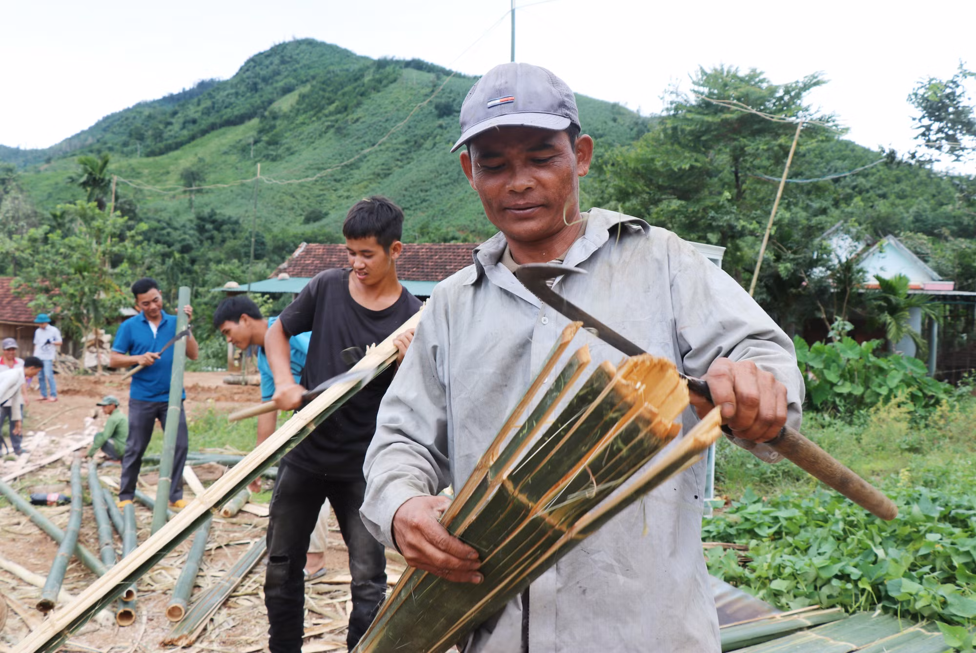 Không ai bảo ai, mỗi người một tay vót tre dựng lại ngôi nhà của gia đình bà Đinh Thị Xấu bị sập sau bão Noru. Ảnh: Phạm Cường - TTXVN