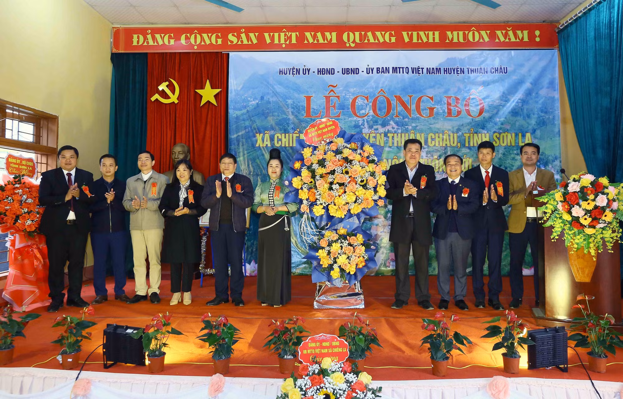 Lãnh đạo huyện Thuận Châu tặng hoa chúc mừng xã Chiềng Pha đạt chuẩn nông thôn mới. Ảnh: Quang Quyết - TTXVN