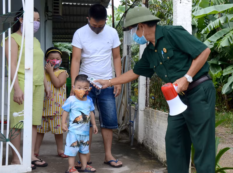 Cựu chiến binh Nguyễn Tiến Ca, Tổ trưởng Tổ dân phố 22 ,phường Hòa Phát, quận Cẩm Lệ, thành phố Đà Nẵng, kiểm tra thân nhiệt cho một hộ gia đình.