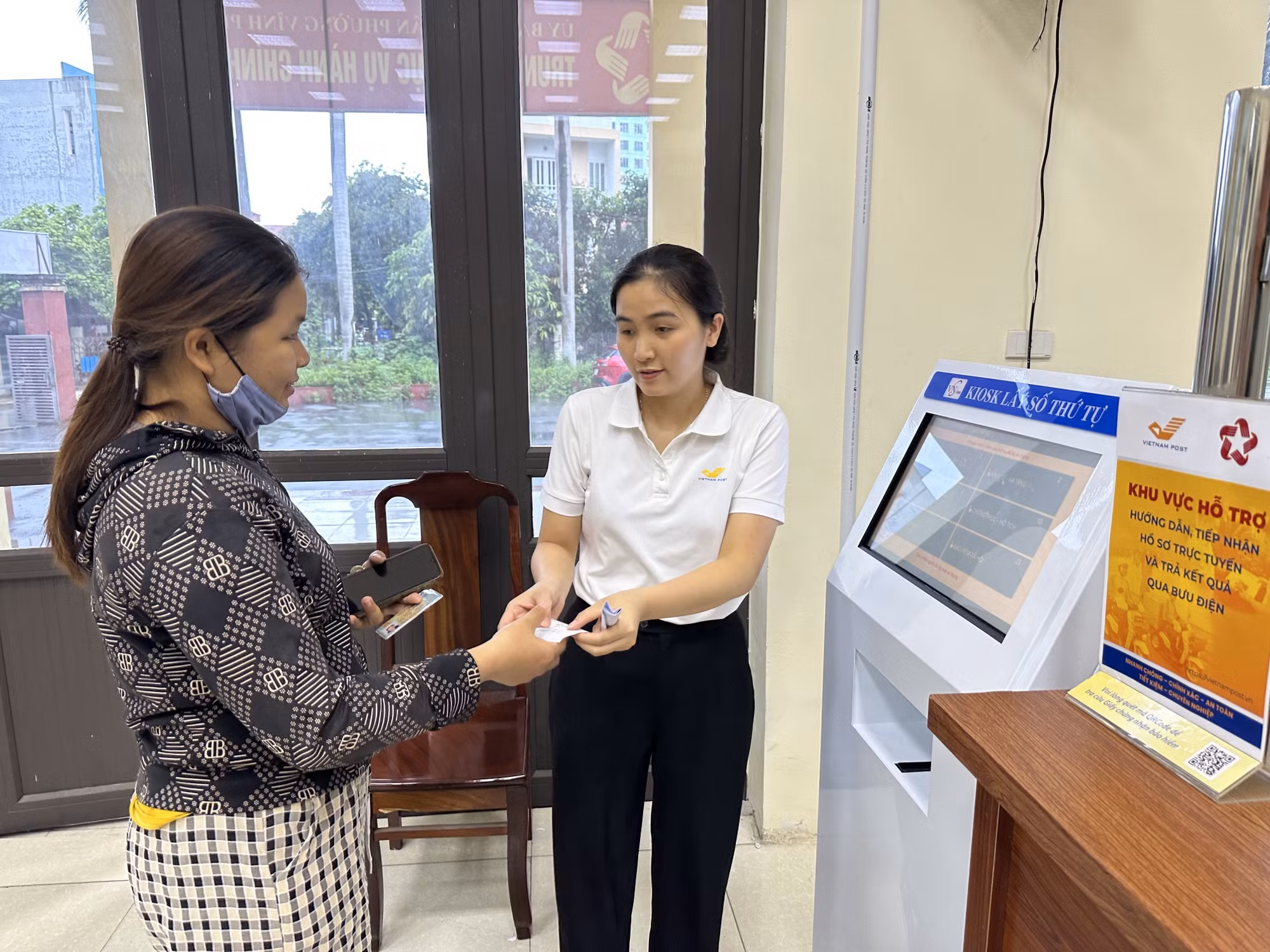 Cán bộ phường Vĩnh Phúc, tỉnh Phú Thọ hỗ trợ người dân đăng kí, lấy số khi làm thủ tục hành chính.
