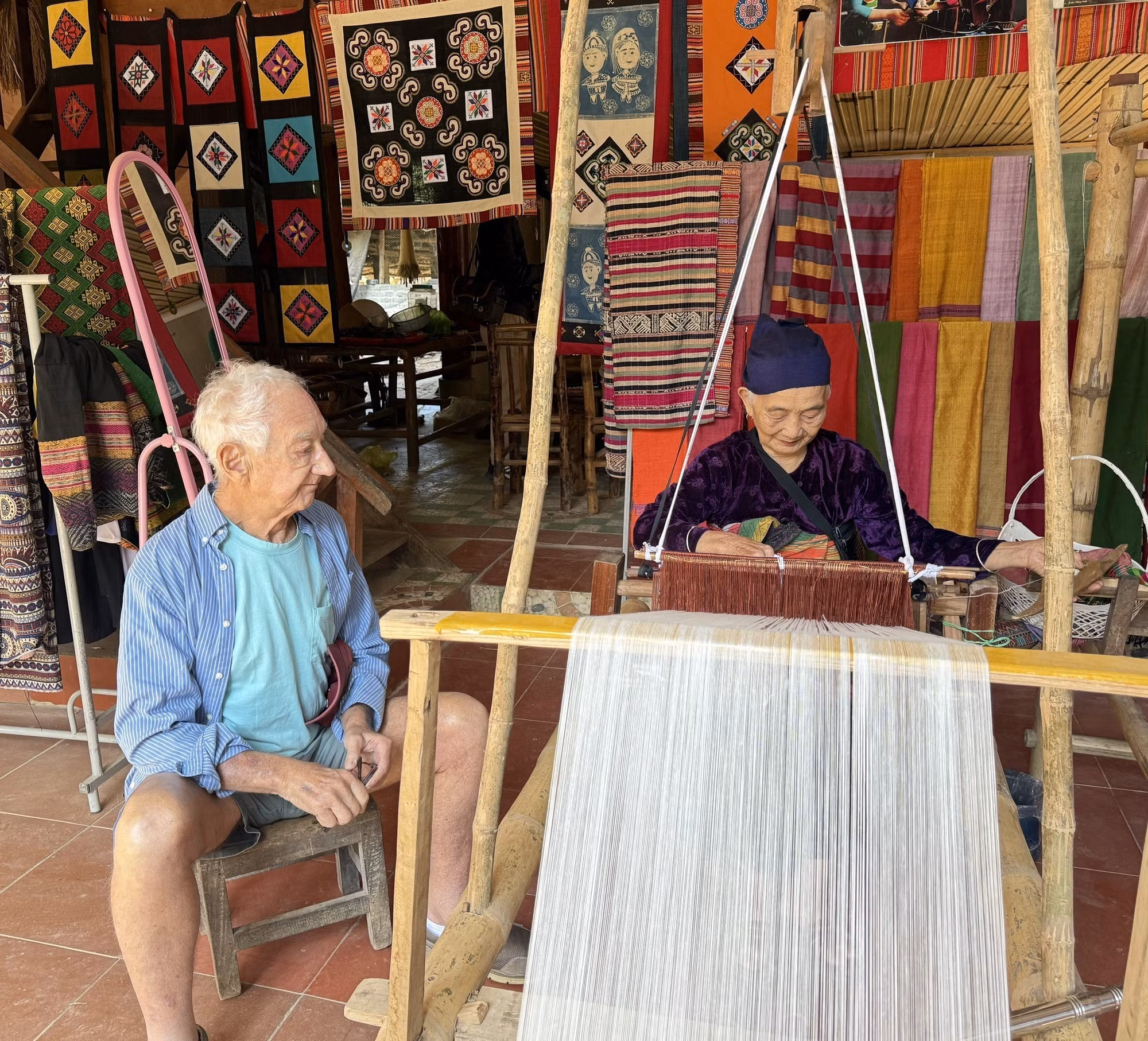 Ông Roistacher Bob (82 tuổi), một du khách Mỹ, rất ấn tượng với đôi bàn tay khéo léo của cụ bà Hà Thị Nhân khi dệt vải.