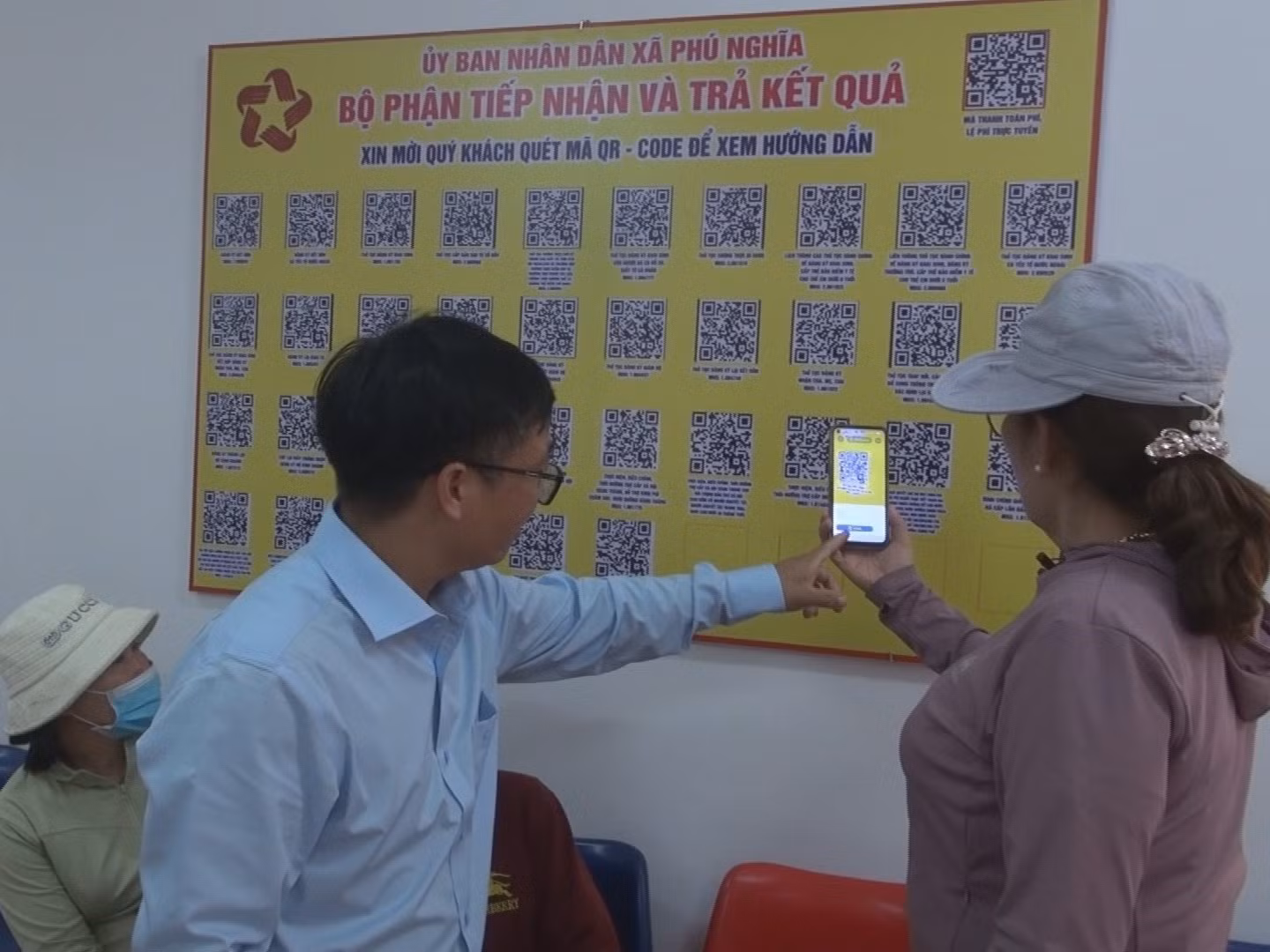 Cán bộ Trung tâm phục vụ Hành chính công xã Phú Nghĩa hướng dẫn người dân quét mã QR về thông tin các lĩnh vực.