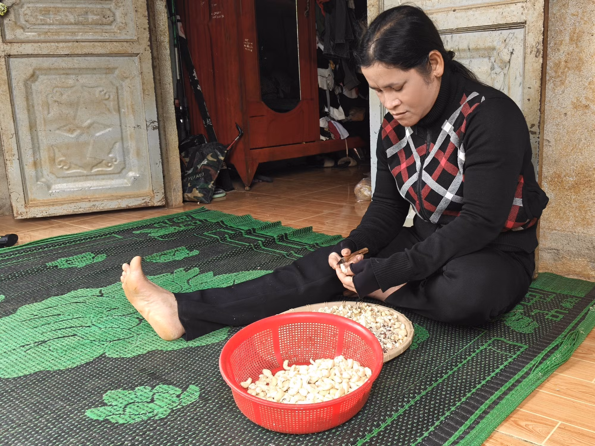 Hộ gia đình bà Thị Man, thôn Bom Bo, xã Bom Bo làm thêm cạo vỏ lụa điều kiếm thu nhập sau khi được nhà nước hỗ trợ xây nhà, bò giống.