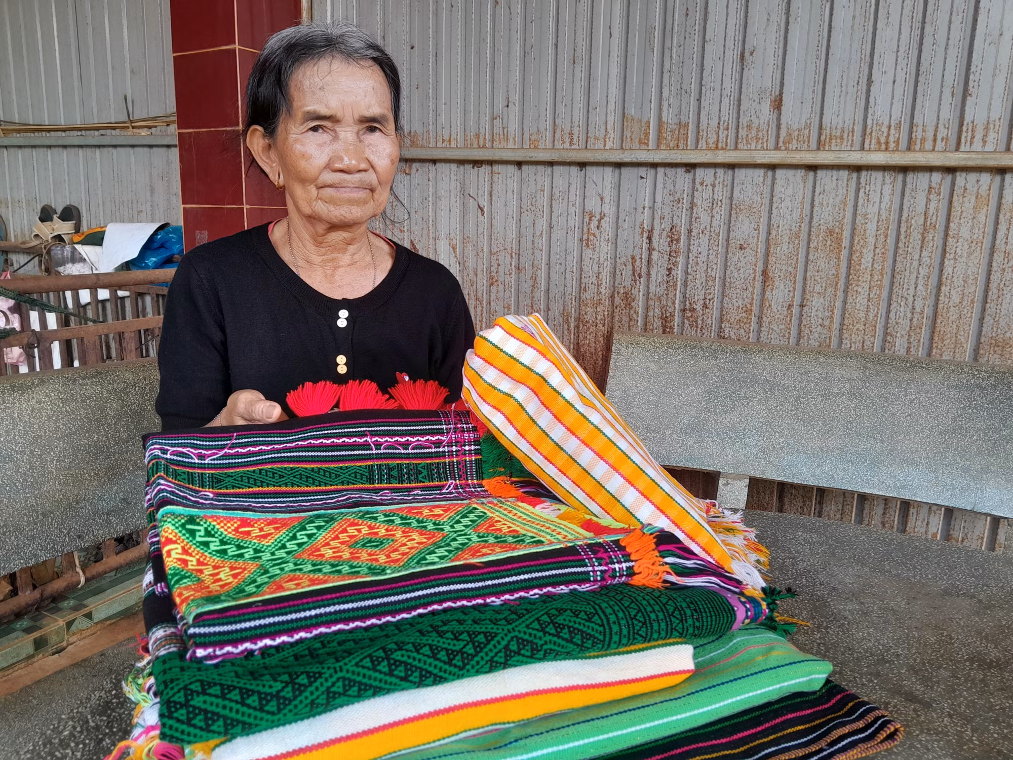 Bà Thị Y Rơ (76 tuổi, người dân tộc M’nông) với tấm thổ cẩm đã dệt hoàn chỉnh.