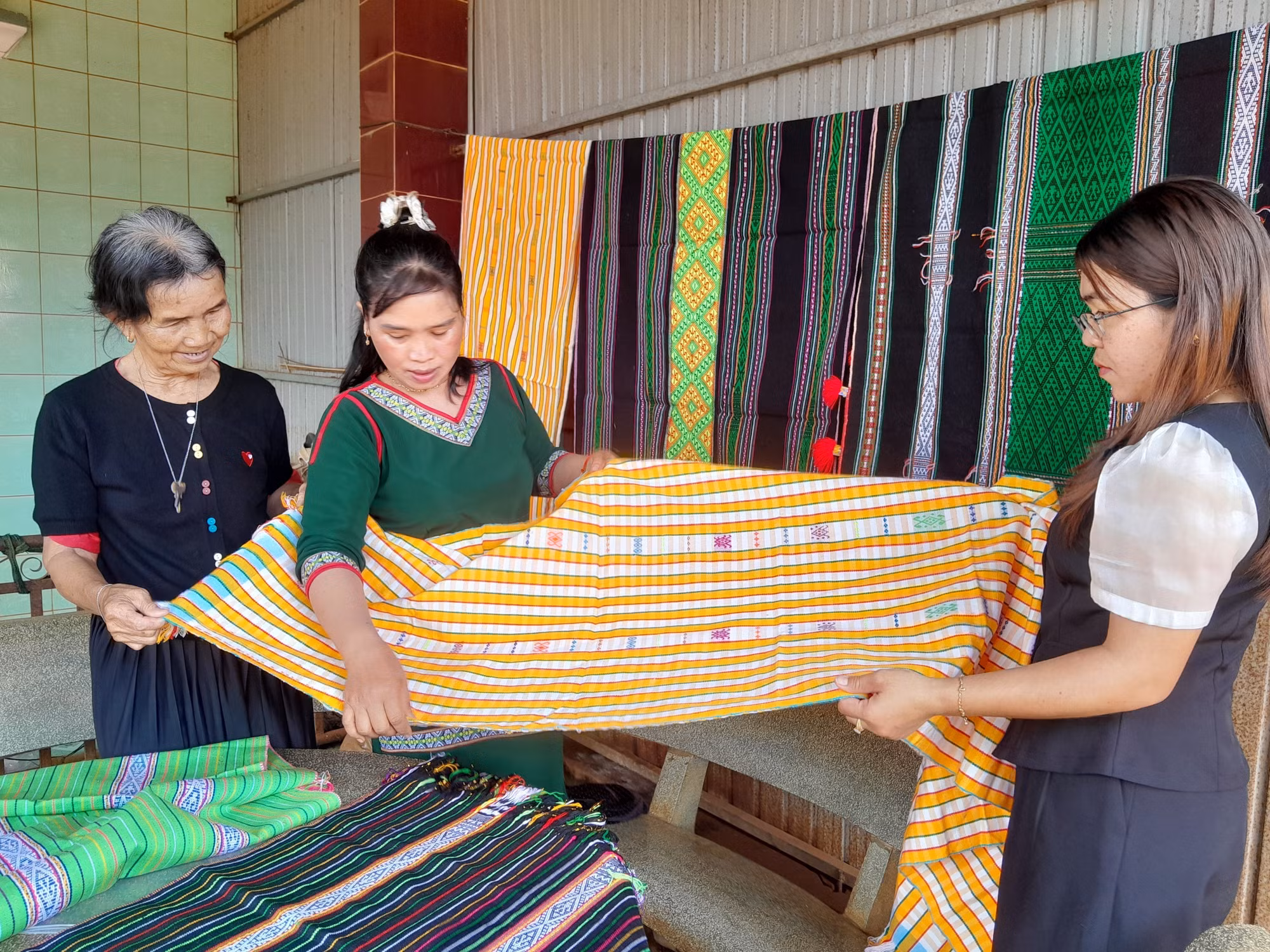 Bà Thị Y Rơ (trái) giới thiệu tấm thổ cẩm đã hoàn chỉnh cho chuyên viên phòng văn hóa-xã hội xã Bù Gia Mập.