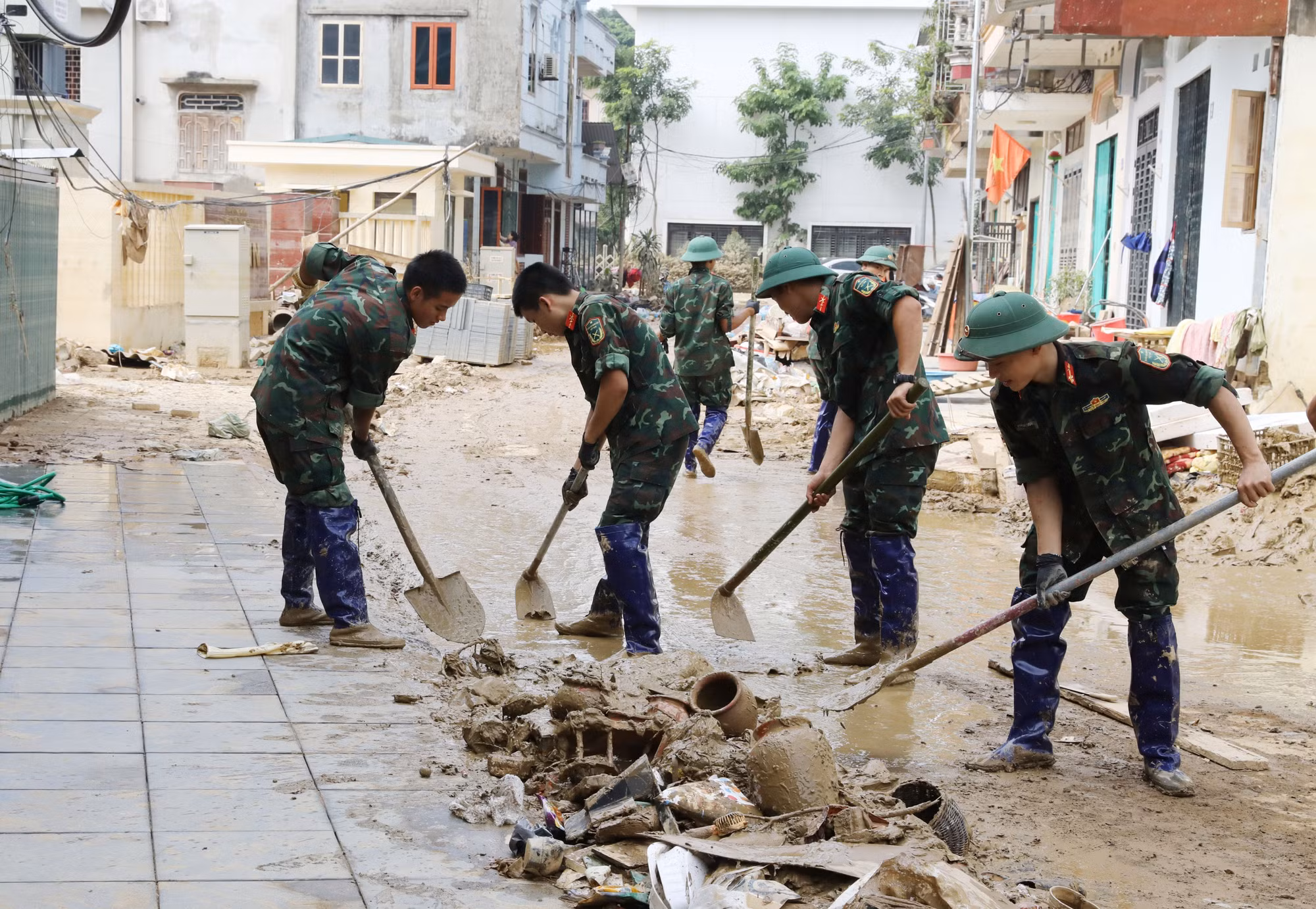 Các chiến sĩ Quân đội dọn dẹp bùn đất, vệ sinh môi trường sau mưa lũ trên phố Nhị Quỹ, phường Phan Đình Phùng.