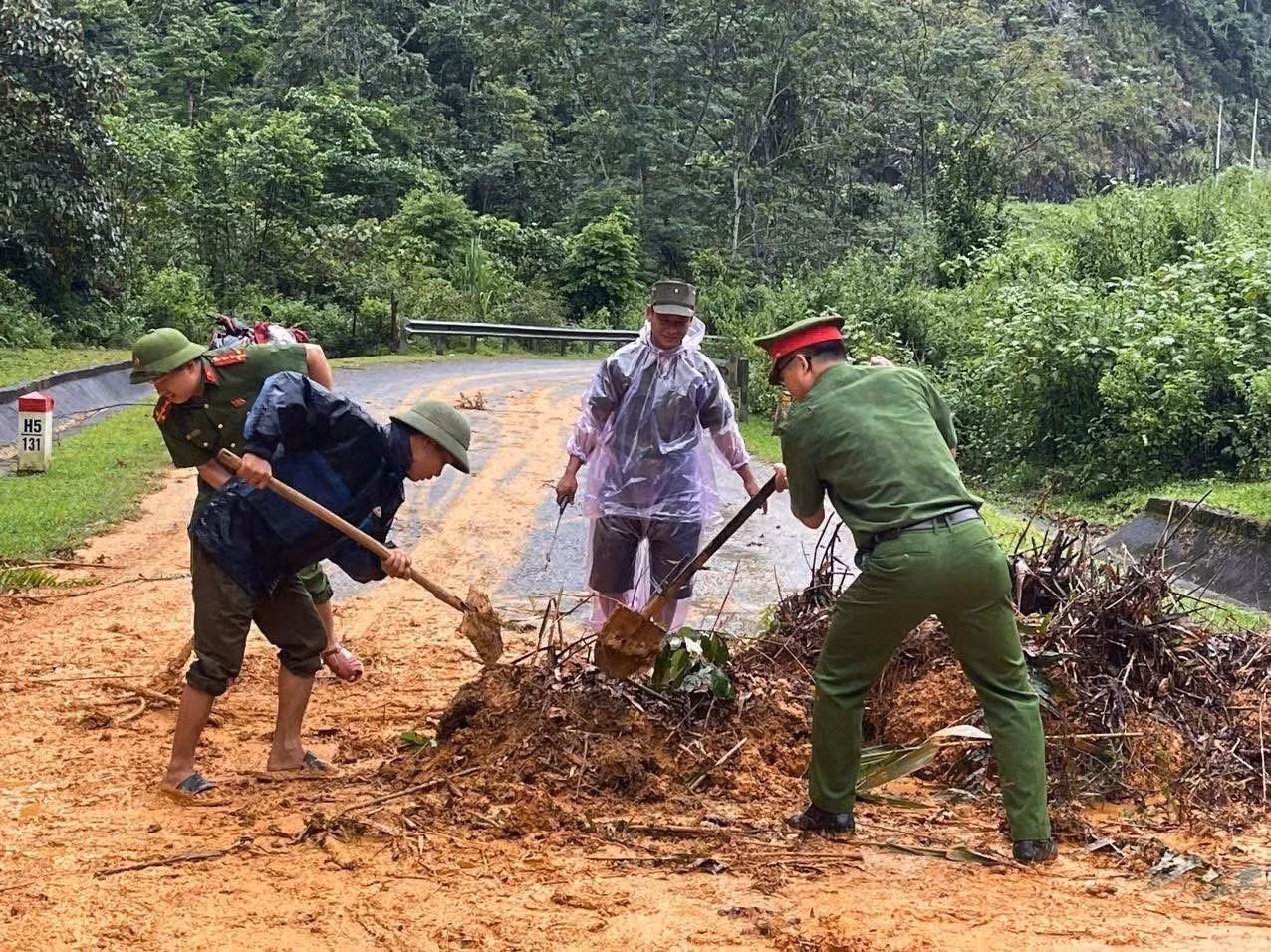 Cán bộ, chiến sĩ công an các xã của tỉnh Tuyên Quang cùng người dân san gạt đất đá, khơi thông tuyến đường bị sạt lở do mưa lũ. Ảnh: TTXVN phát