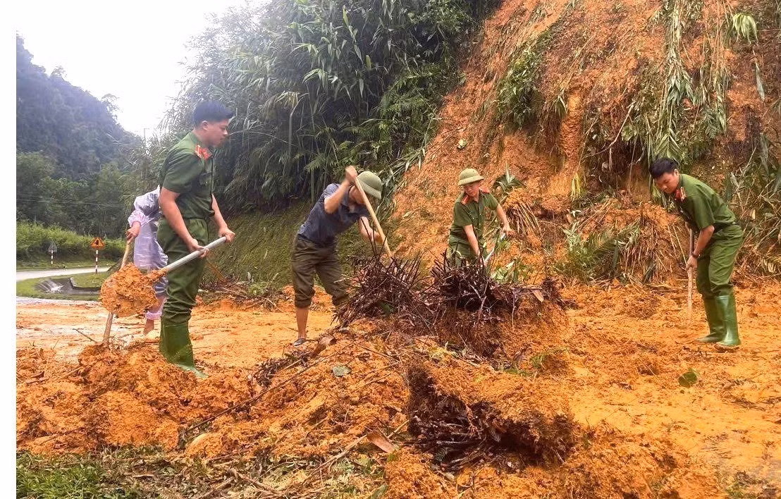 Lực lượng công an cơ sở phối hợp với nhân dân dọn dẹp đất đá, khắc phục điểm sạt lở trên tuyến đường bị ảnh hưởng bởi mưa lũ tại tỉnh Tuyên Quang. Ảnh: TTXVN phát