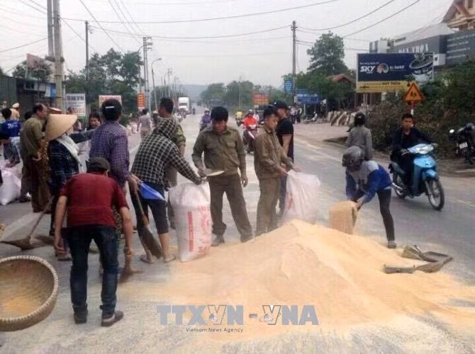 Lực lượng công an và người dân giúp chủ xe container thu gom cám bị đổ trên đường ảnh 1