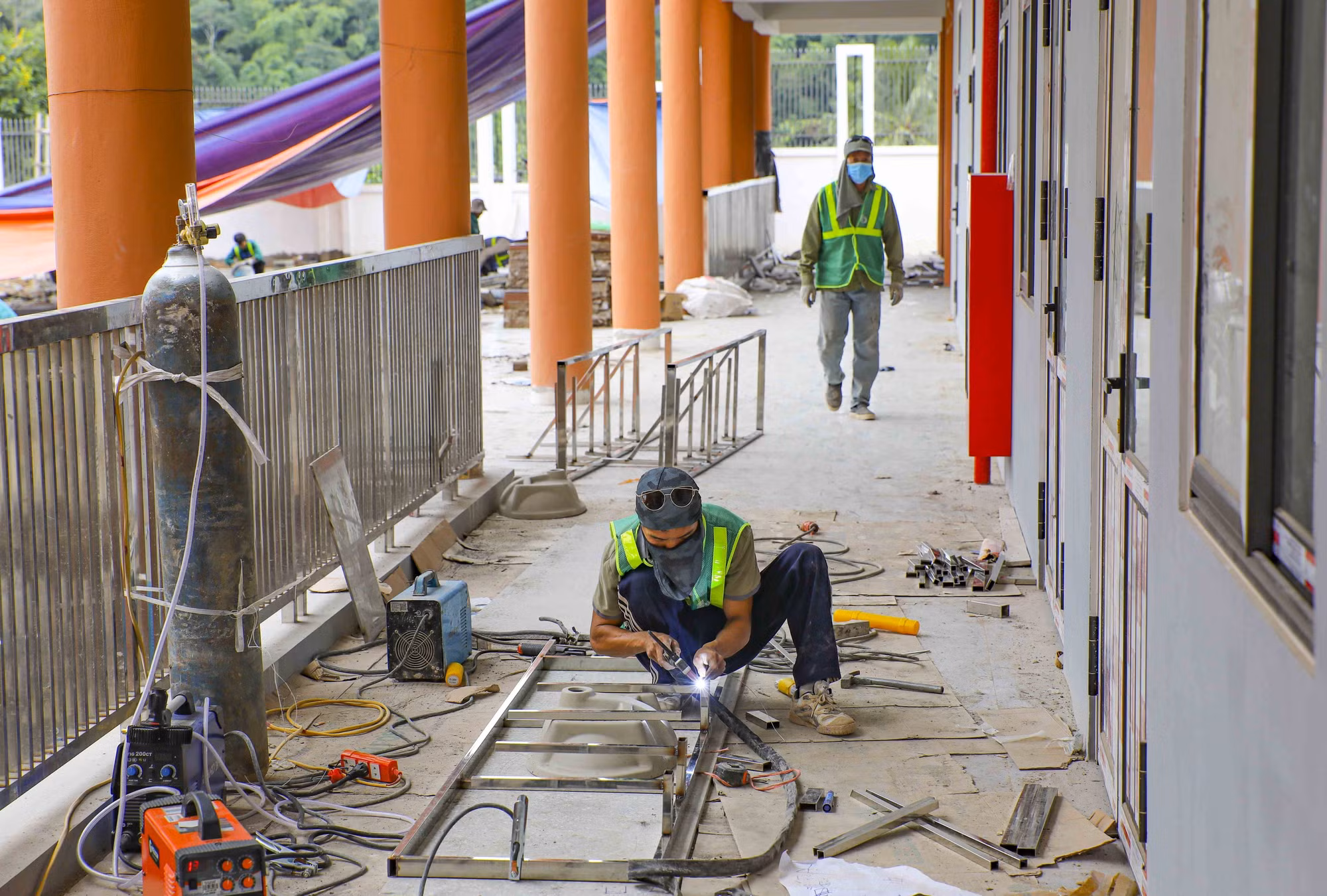 Công nhân thi công hoàn thiện lan can hành lang khu lớp học, khẩn trương hoàn thành các hạng mục cuối trước thời điểm bàn giao công trình.