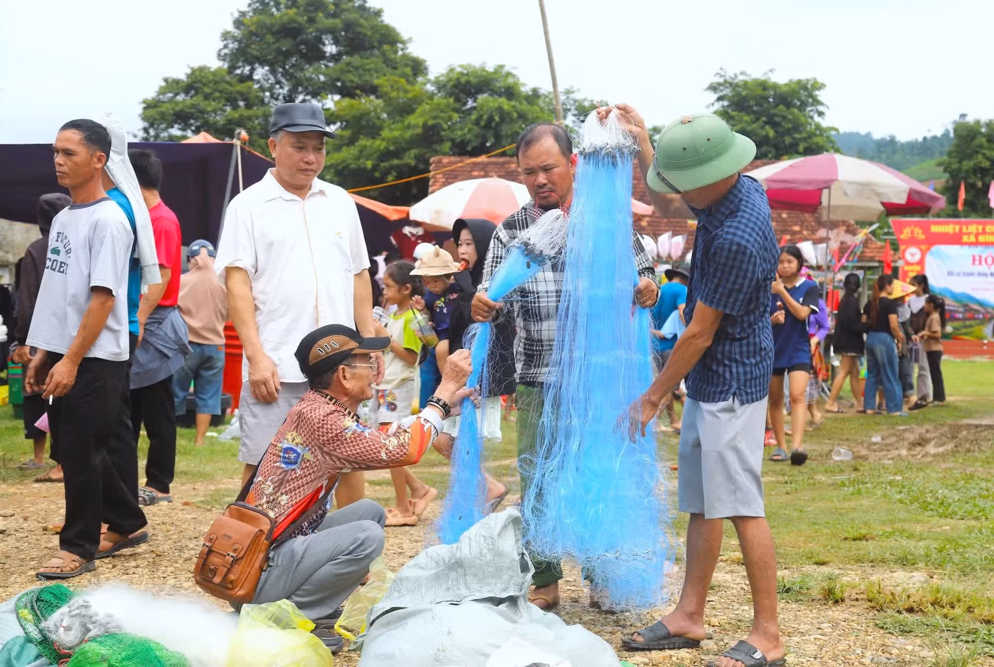 Nhiều đàn ông đang lựa chọn kỹ độ mảnh của sợi đan, kích thước mắt lưới trên từng tấm lưới để mua về phục vụ công việc đánh bắt cá trên sông, suối. Ảnh: Xuân Tiến/TTXVN