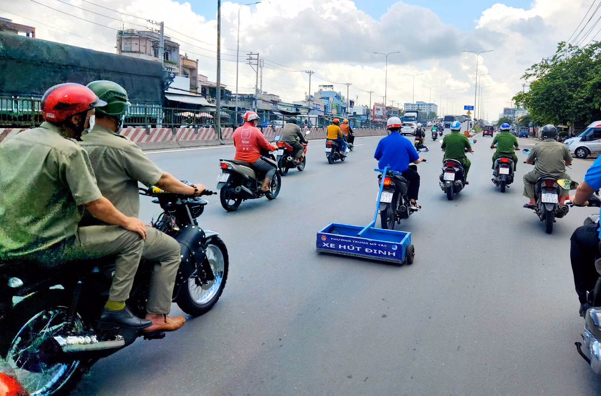 Lực lượng Công an phường Trung Mỹ Tây cùng Đoàn thanh niên phường chạy xe hút đinh trên Quốc lộ 1 đoạn qua địa bàn Quận 12.