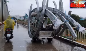 Xe 3 bánh thương binh chở khung sắt uốn hình quá khổ lao vun vút trên cầu Chương Dương (quận Long Biên), mặc dù trời mưa, đường trơn trượt.