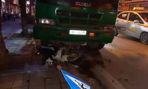 Xe chở rác cán nát xe máy đang dừng chờ đèn đỏ, đâm đổ cột đèn
