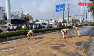 Cảnh sát giao thông đội nắng rải cát lên mặt đường trơn trượt do dầu ăn