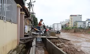 Đường cao hơn nền nhà gần 1m, người dân chật vật bắc cầu để đi lại