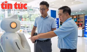 Cán bộ Trung tâm Phụ vụ hành chính TP Hà Nội hướng dẫn người dân tra cứu quy trình nộp hồ sơ trên robot AI.