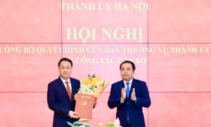 Bí thư Thành ủy Hà Nội Trần Đức Thắng trao quyết định và tặng hoa chúc mừng ông Trần Đình Cảnh. Ảnh Quang Thái