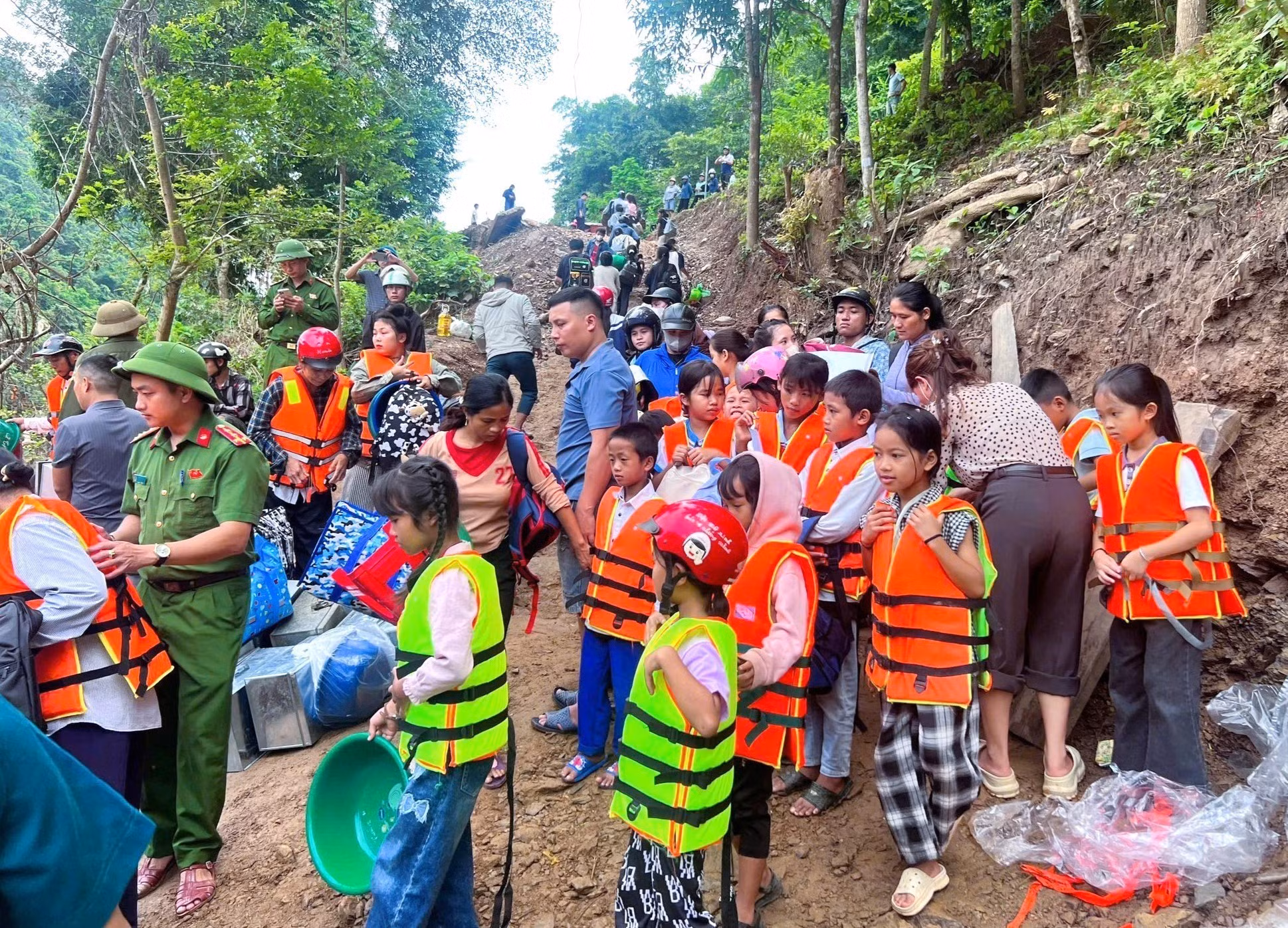 Lực lượng chức năng hỗ trợ đưa học sinh, giáo viên qua sông đến trường bằng thuyền. Ảnh: TTXVN phát