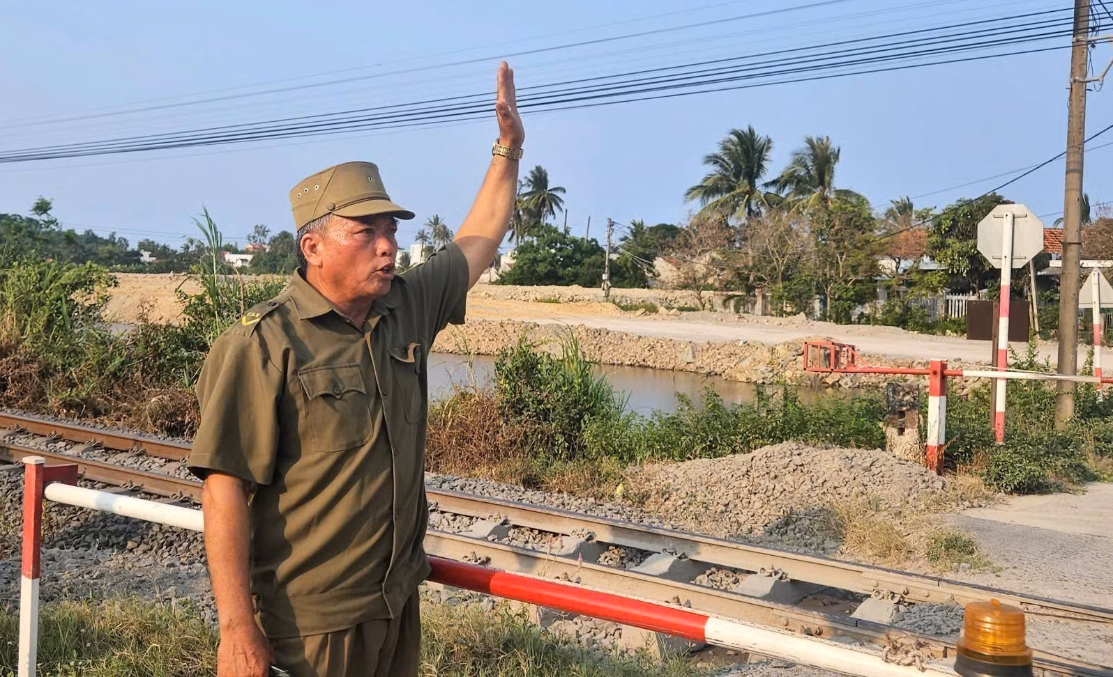 Ông Nguyễn Văn Sang, thành viên tổ “gác chắn tự quản” ra hiệu an toàn cho tàu đi qua.