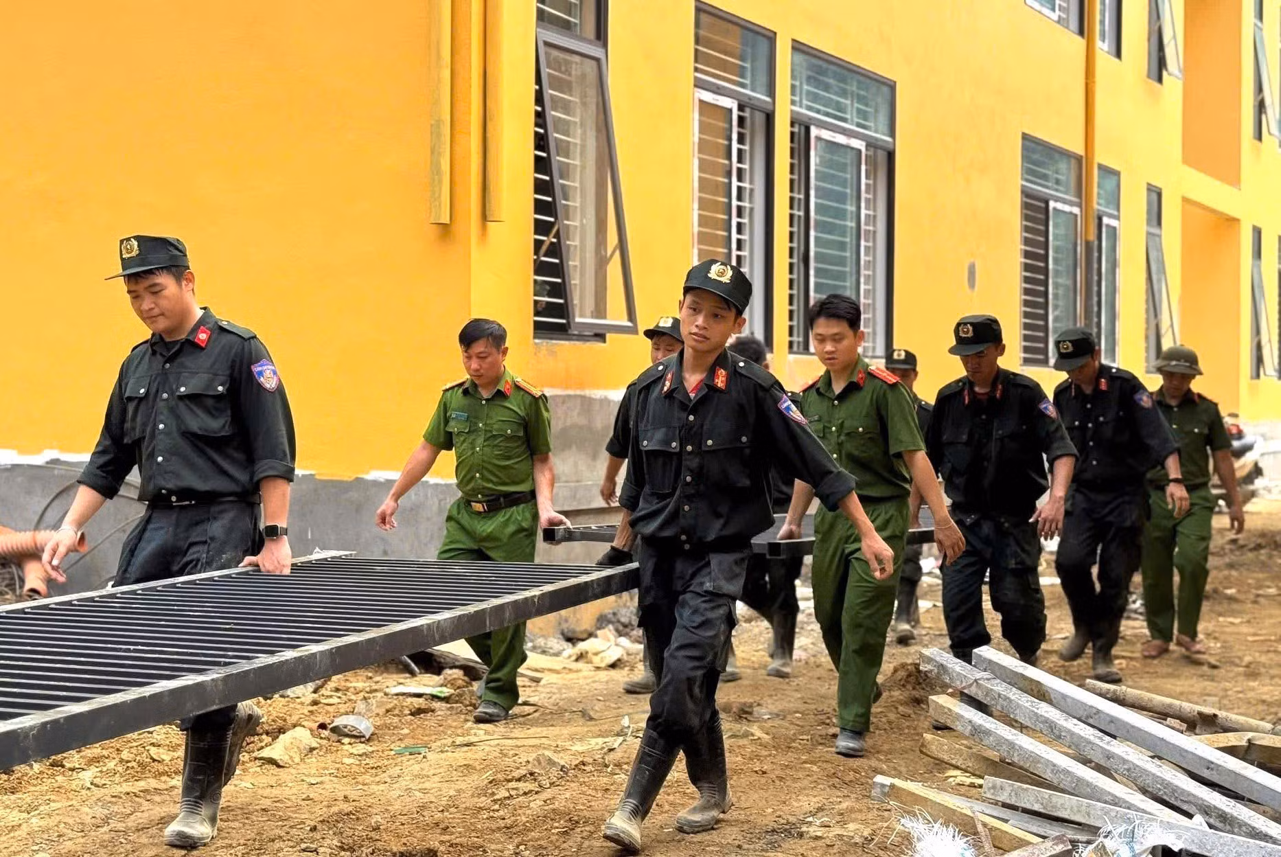 Cán bộ, chiến sĩ Phòng Cảnh sát cơ động thu gom vật liệu, dọn dẹp mặt bằng tại công trình Trường Phổ thông nội trú liên cấp Tiểu học và Trung học cơ sở Minh Tân, xã Minh Tân (tỉnh Tuyên Quang).