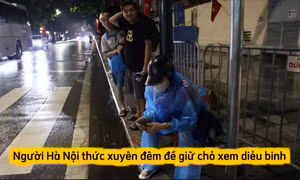 Ngưởi dân mặc áo mưa, che ô... giữ chỗ chờ xem diễu binh tối ngày 27/8.