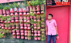 Ông Mai Văn Ngọc mặc áo màu hồng bên căn nhà màu hồng bằng rác thải nhựa.