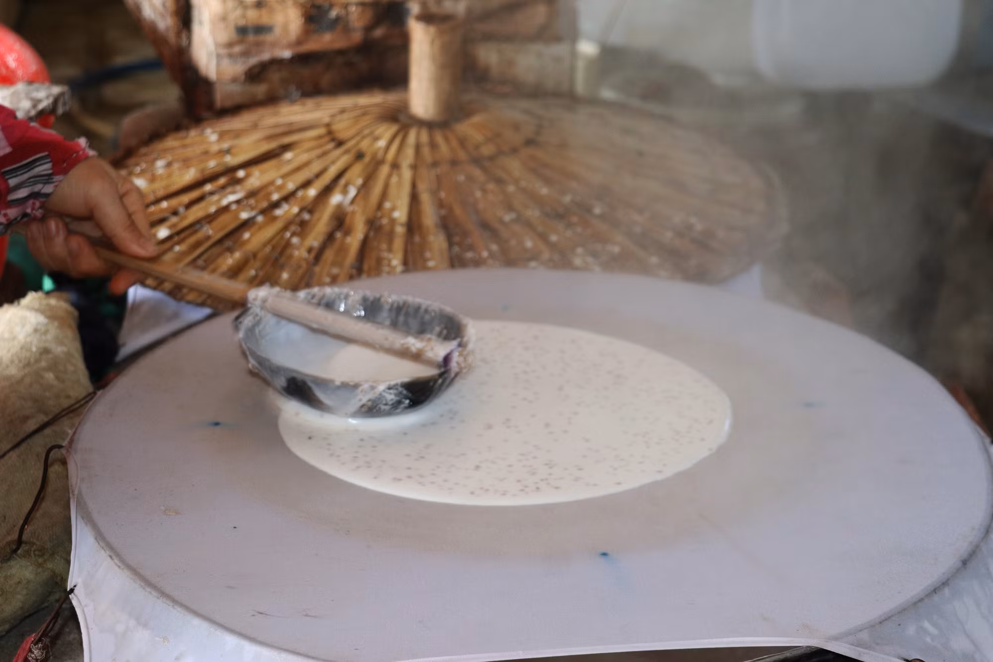Khâu tráng bột được người thợ làm nhanh, đều tay để bánh đảm bảo có độ mòng vừa phải. Ảnh: Hữu Chí – TTXVN